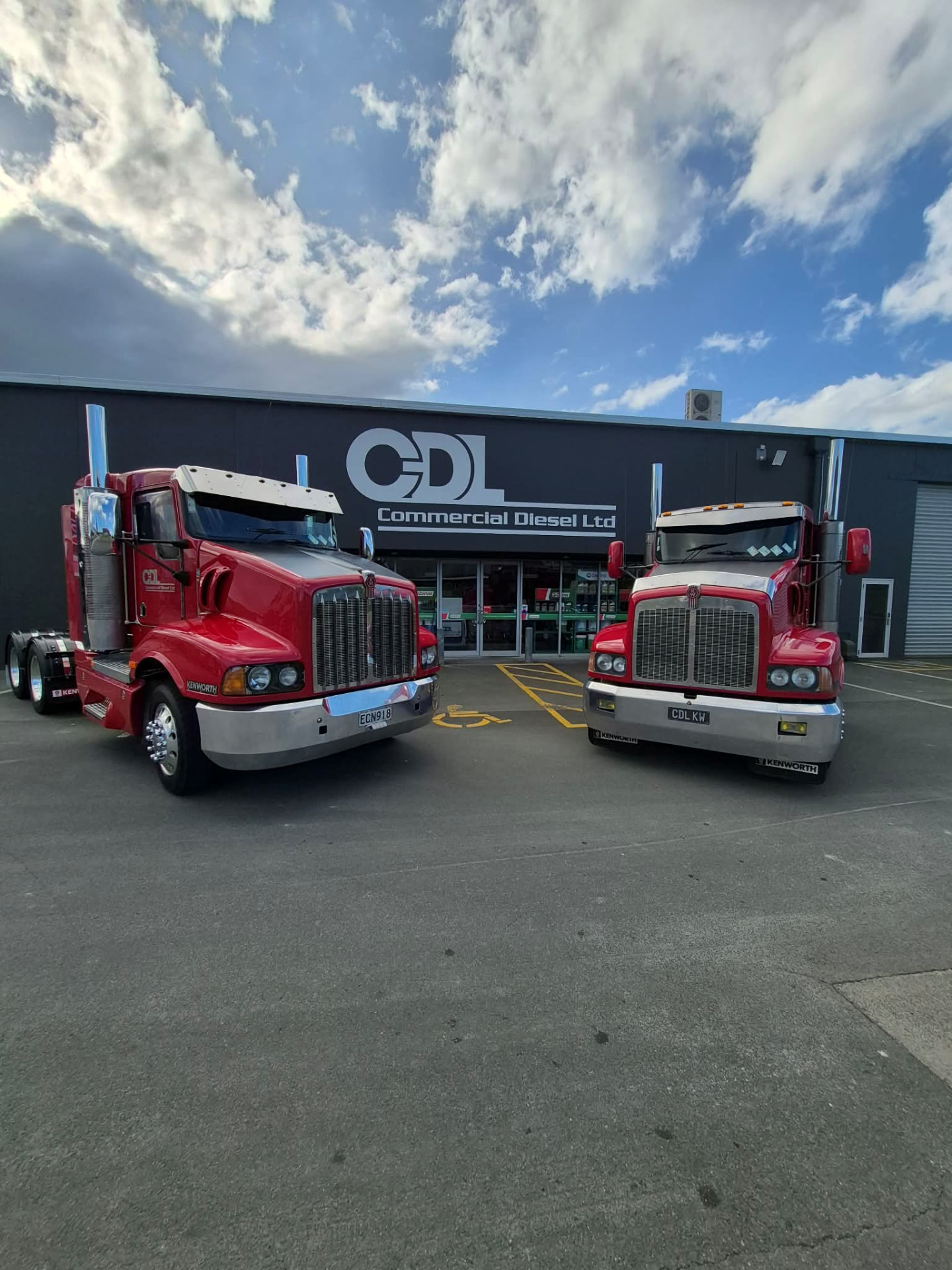 Two red Kenworth trucks parked outside the Commercial Diesel Ltd branch